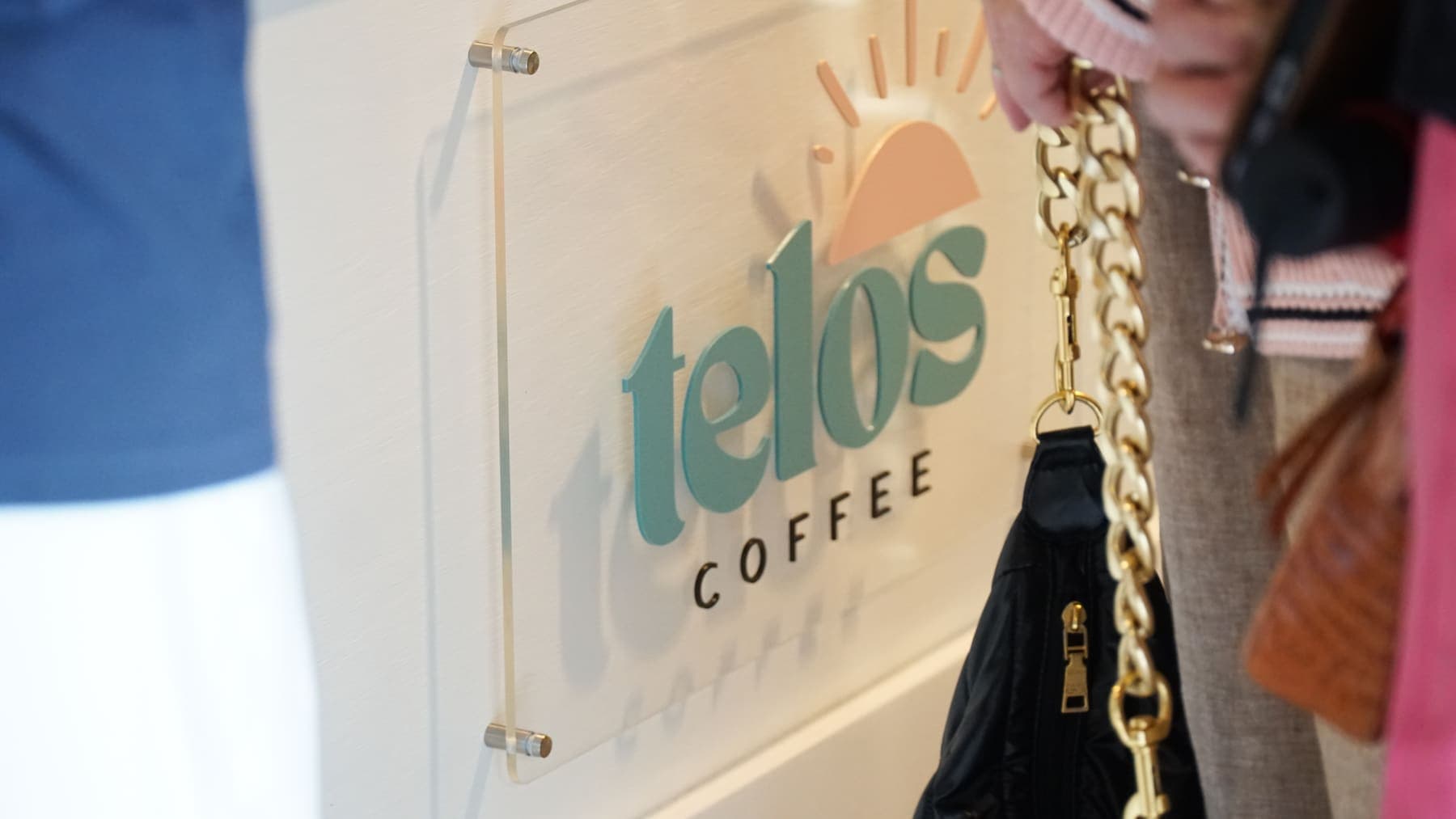 The Telos Coffee logo sign mounted on the front of the cart at an event