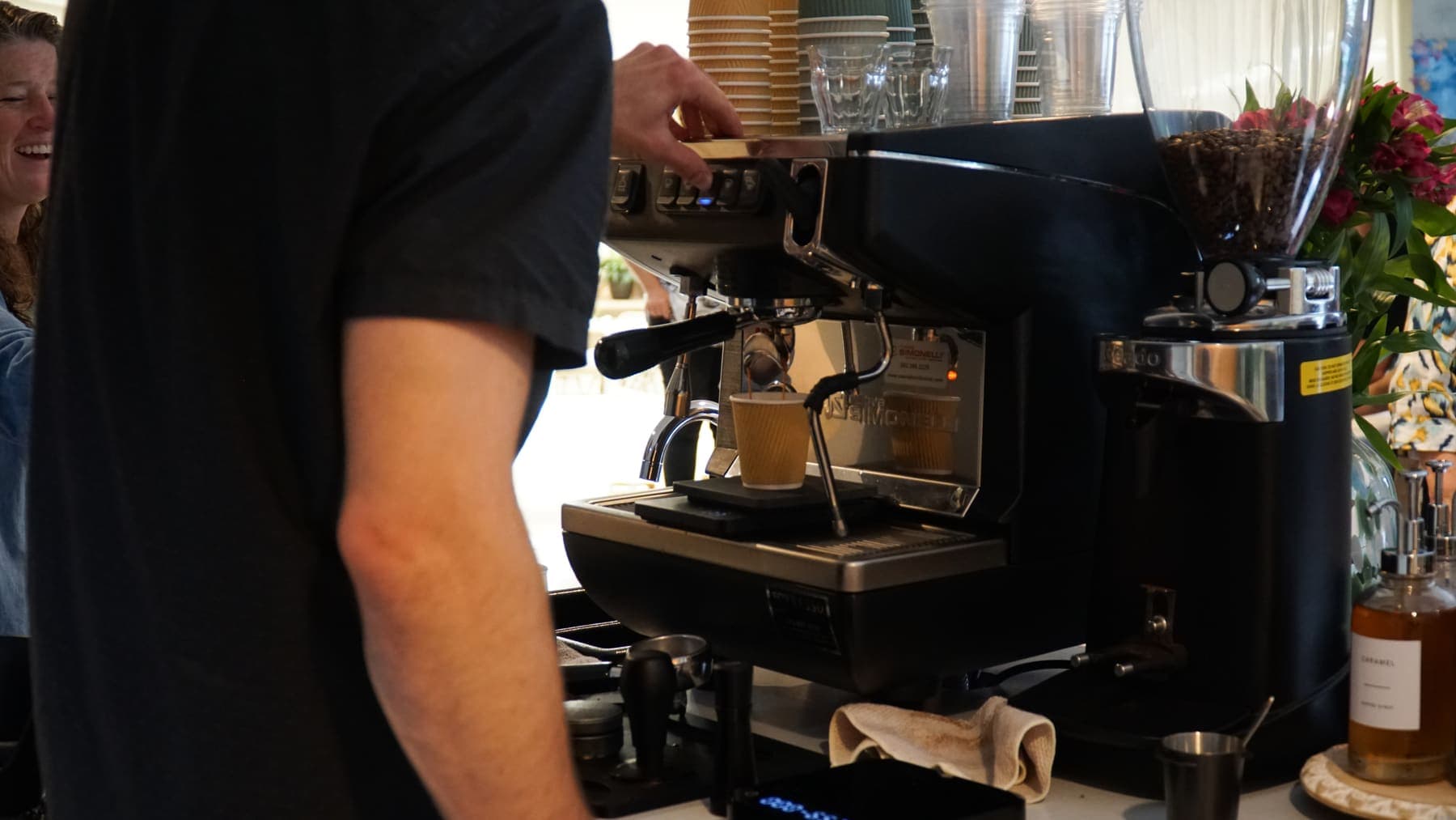 A barista pulling an espresso shot on the commercial machine aboard the cart