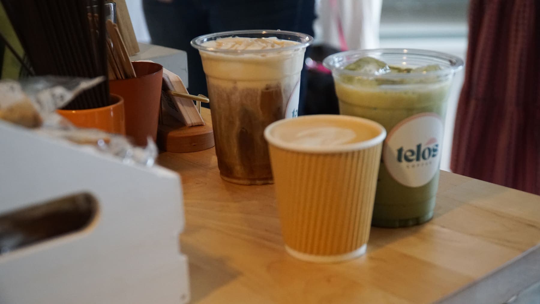 An iced latte, a hot latte and an iced matcha on the counter