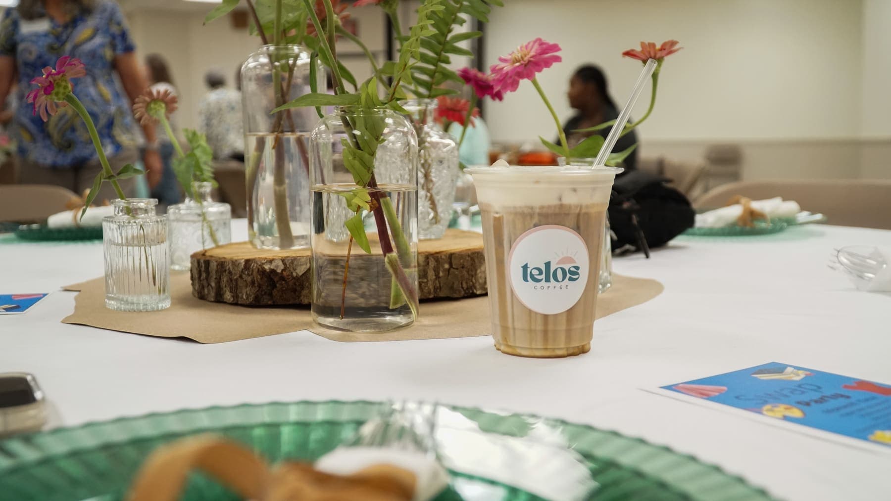A branded iced latte on a set event table with fresh flowers